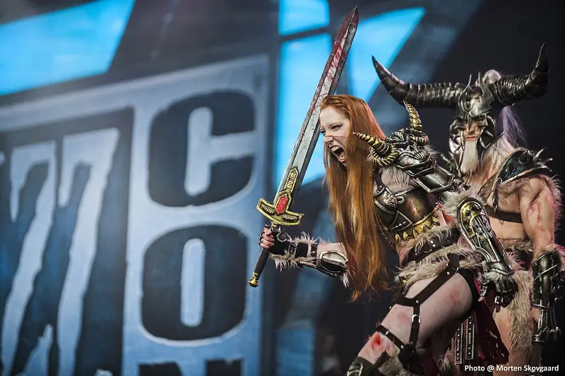Une cosplayeuse en armure de barbare, épée levée, sur scène à la BlizzCon 2013.
