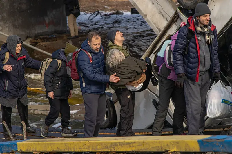 Des civils fuient Irpin le 8 mars 2022 en passant sous le pont bombardé, pendant l'offensive russe sur Kyiv.